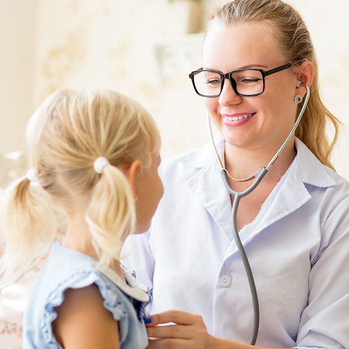 A young girl is listening to a doctor's stethoscope while being screened for Parkinson disease
